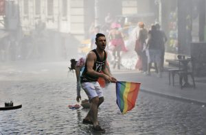 A participant in the Gay Pride event in support of Lesbian, Gay, Bisexual and Transsexual (LGBT) rights reacts as others flee after Turkish police use a water canon to disperse them in Istanbul, Turkey, Sunday, June 28, 2015. Turkish police have used water cannons and tear gas to clear gay pride demonstrators from Istanbul's central square. Between 100 and 200 protestors were chased away from Taksim Square on Sunday after a police vehicle fired several jets of water to disperse the crowd. It wasn't immediately clear why the police intervened to push the peaceful if noisy protest away from the area. (AP Photo/Emrah Gurel)